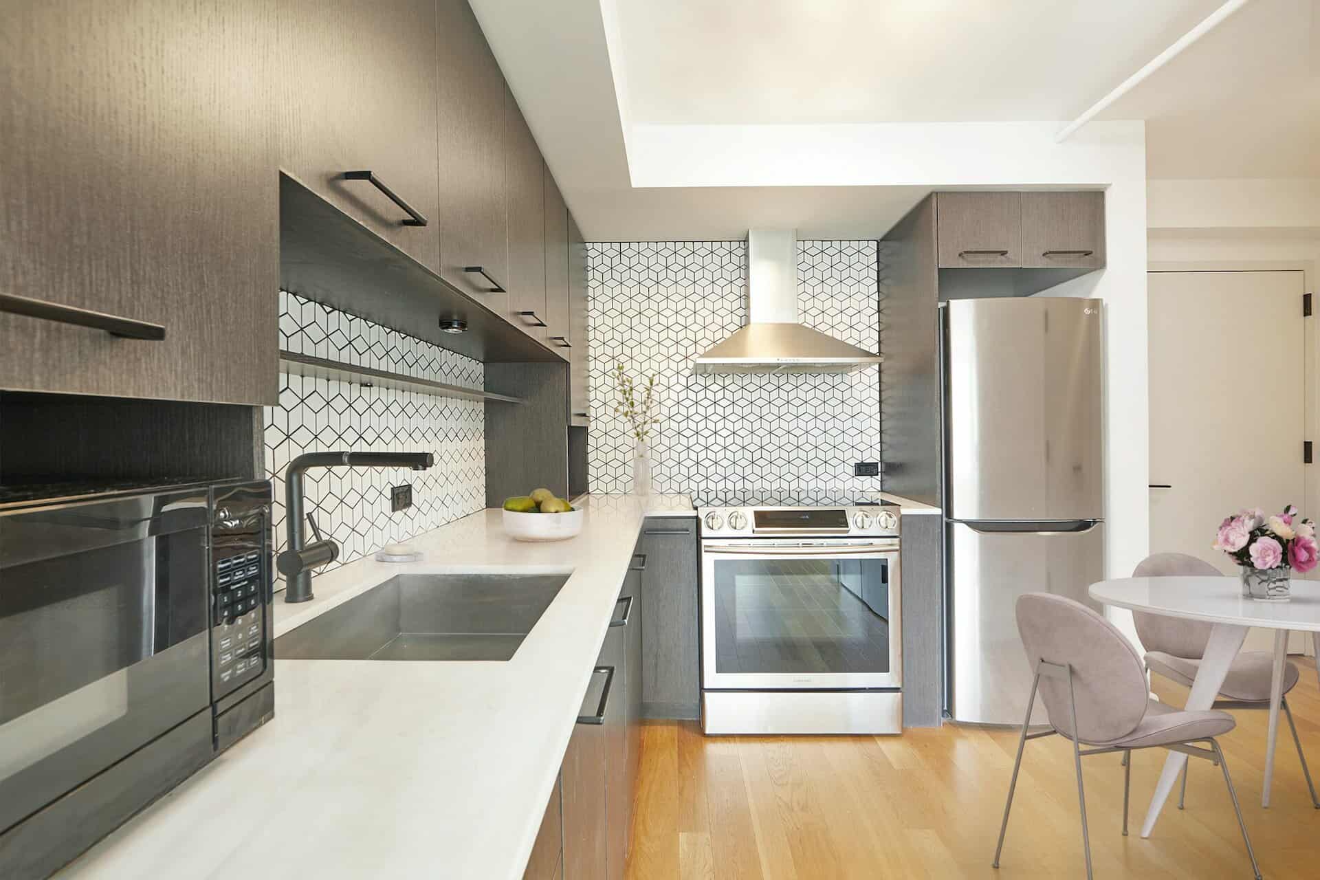 Kitchen at 101 East 10th Street apartments in New York with stainless steel appliances, white countertops & hardwood floors.