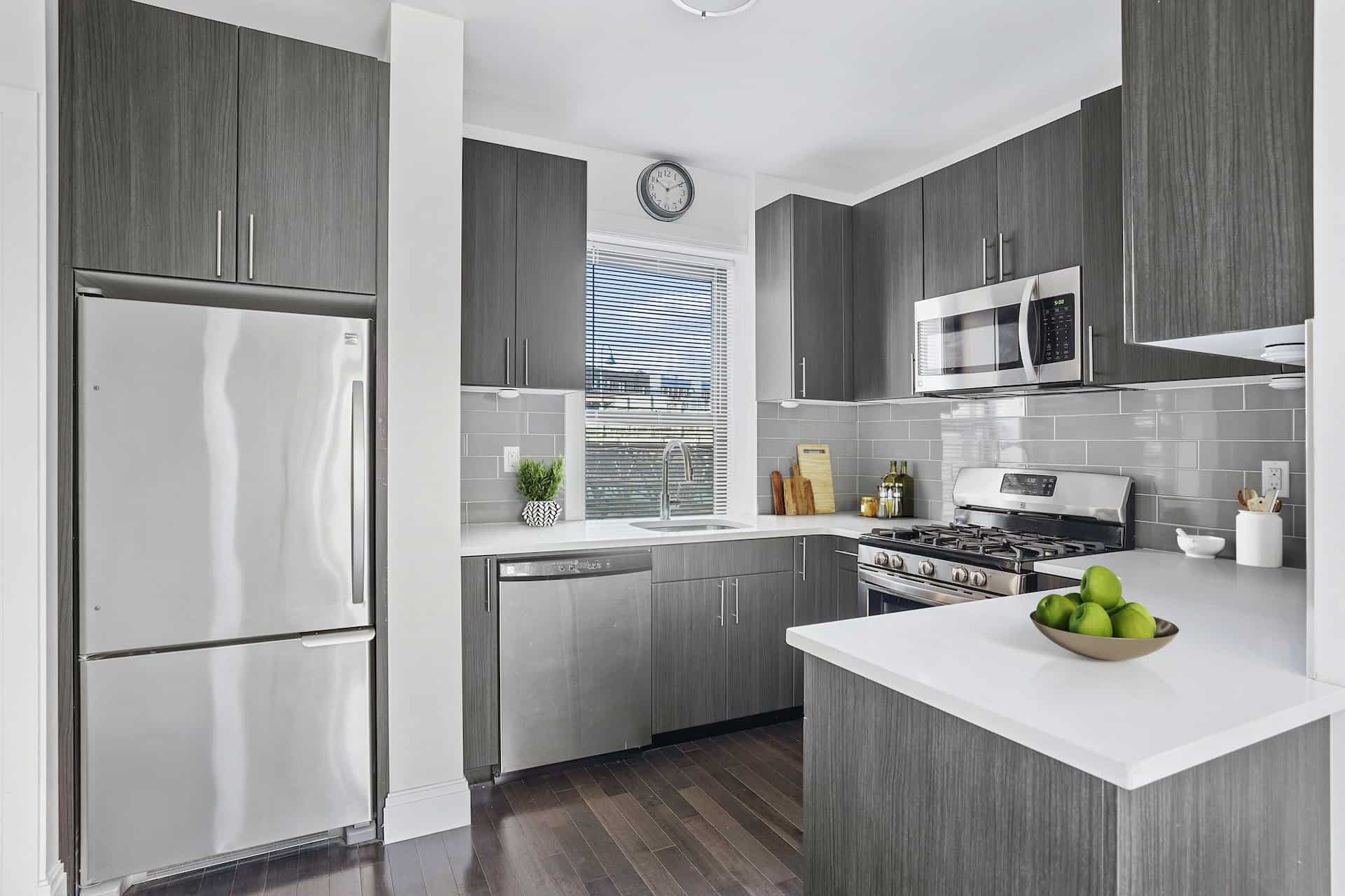Galley kitchen at 556-566 West 126th Street apartments in New York with white stone countertops & stainless steel appliances.