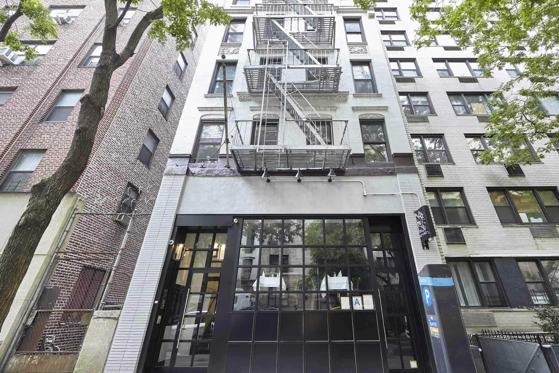 Entrance to 244 East 46th Street apartments in New York. Brick residential building with tall windows and glass door.