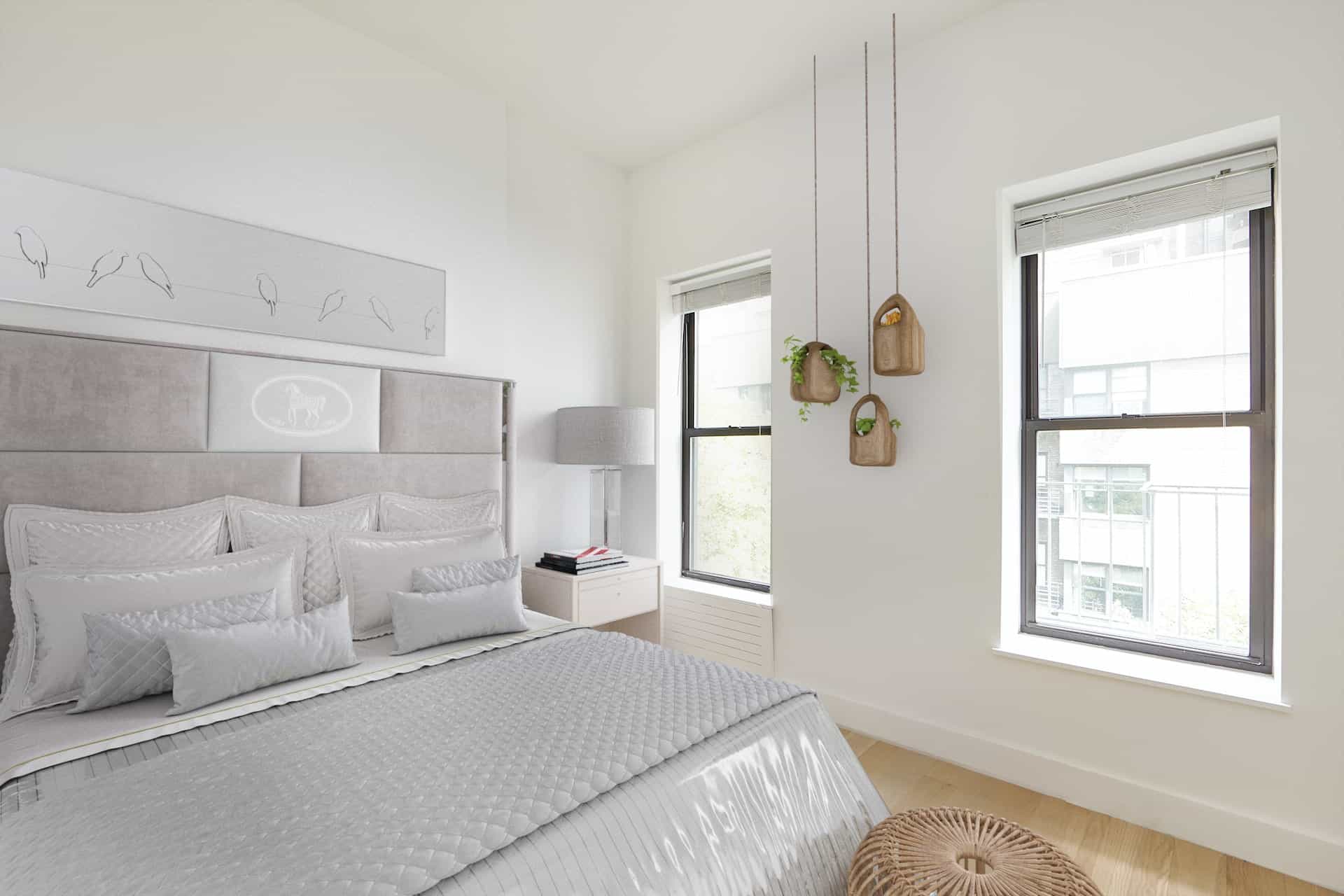Bedroom at 244 East 46th Street apartments with a king-sized bed, oversized headboard, two windows and hardwood floors.