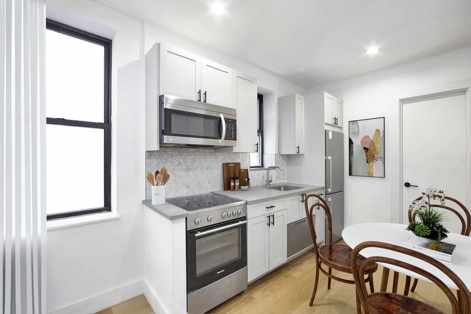Kitchen at 244 East 46th Street apartments with stainless steel appliances, stone countertops, a window and hardwood floors.