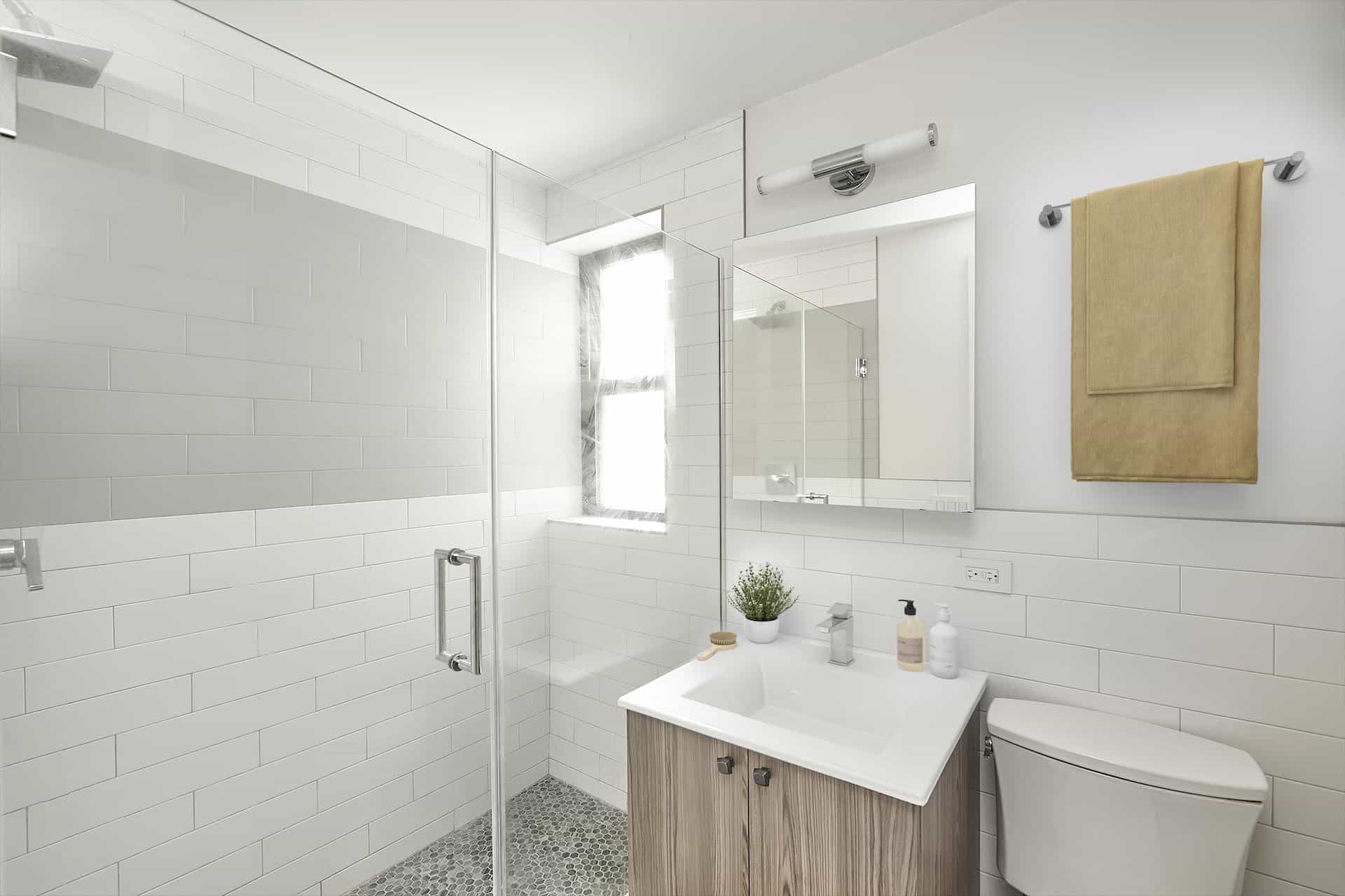 Bathroom at 244 East 46th Street apartments in Turtle Bay with a single vanity, square mirror & walk-in shower with a window.