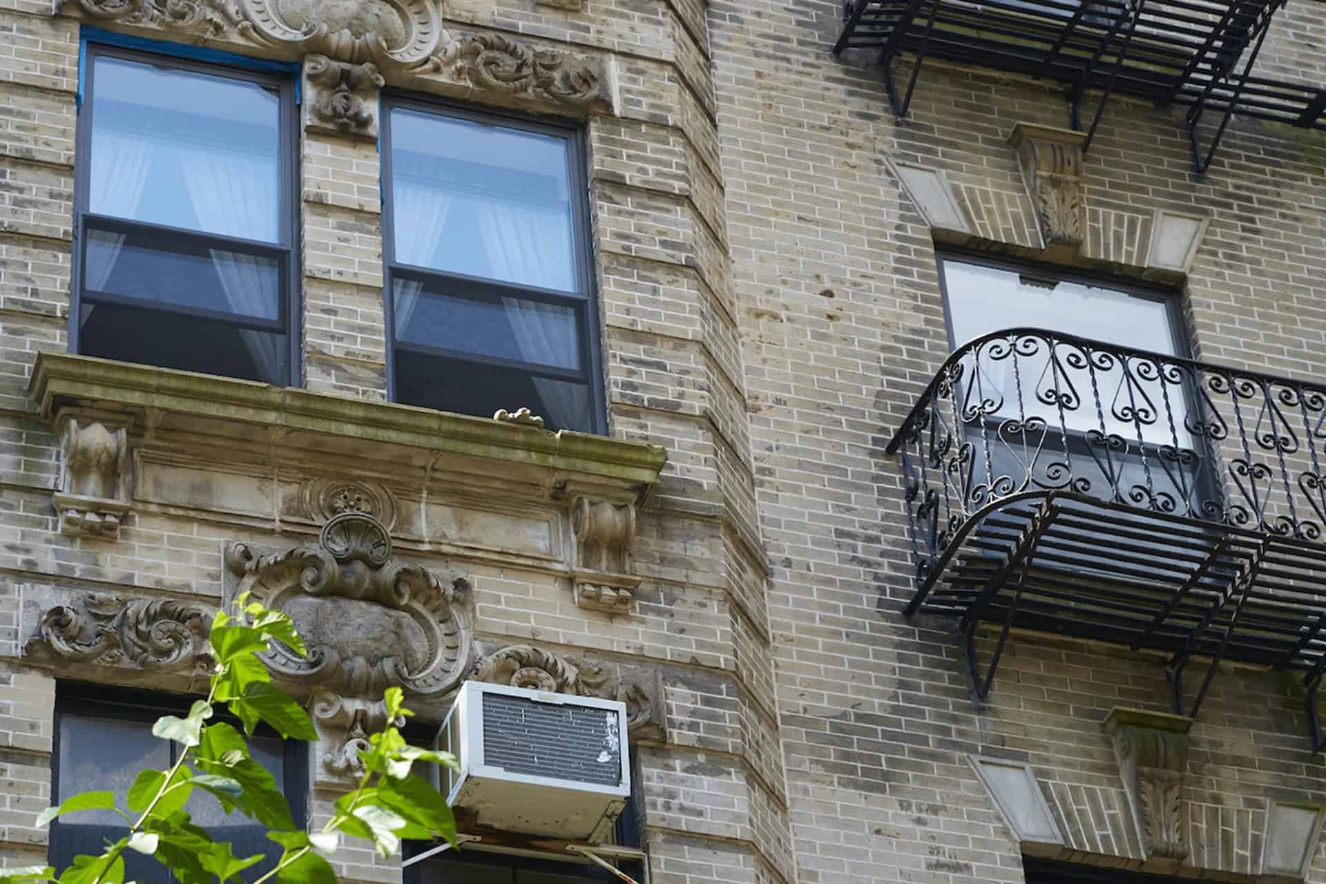 Close up of 244 East 7th Street building exterior. Brick apartment building in New York with iron balcony and large windows.