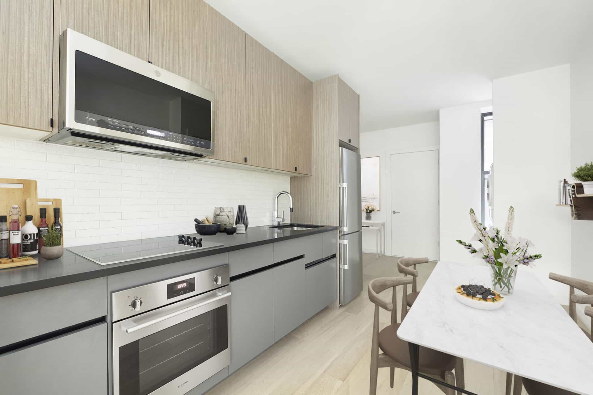 Kitchen at 244 East 7th Street apartments in New York. Open kitchen with stainless steel appliances and dining table.