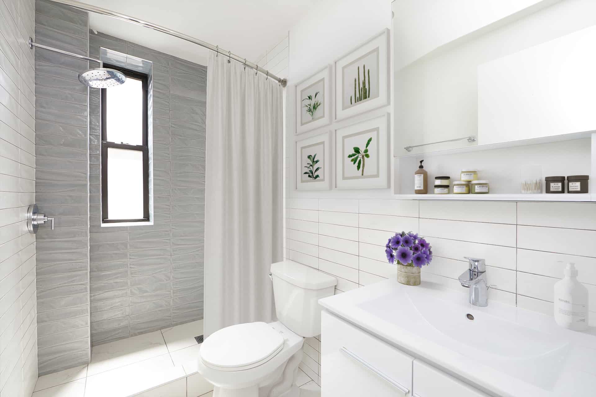 Bathroom at 245 East 30th Street apartments in Kips Bay with tile walls, single vanity, and walk-in shower with a window.