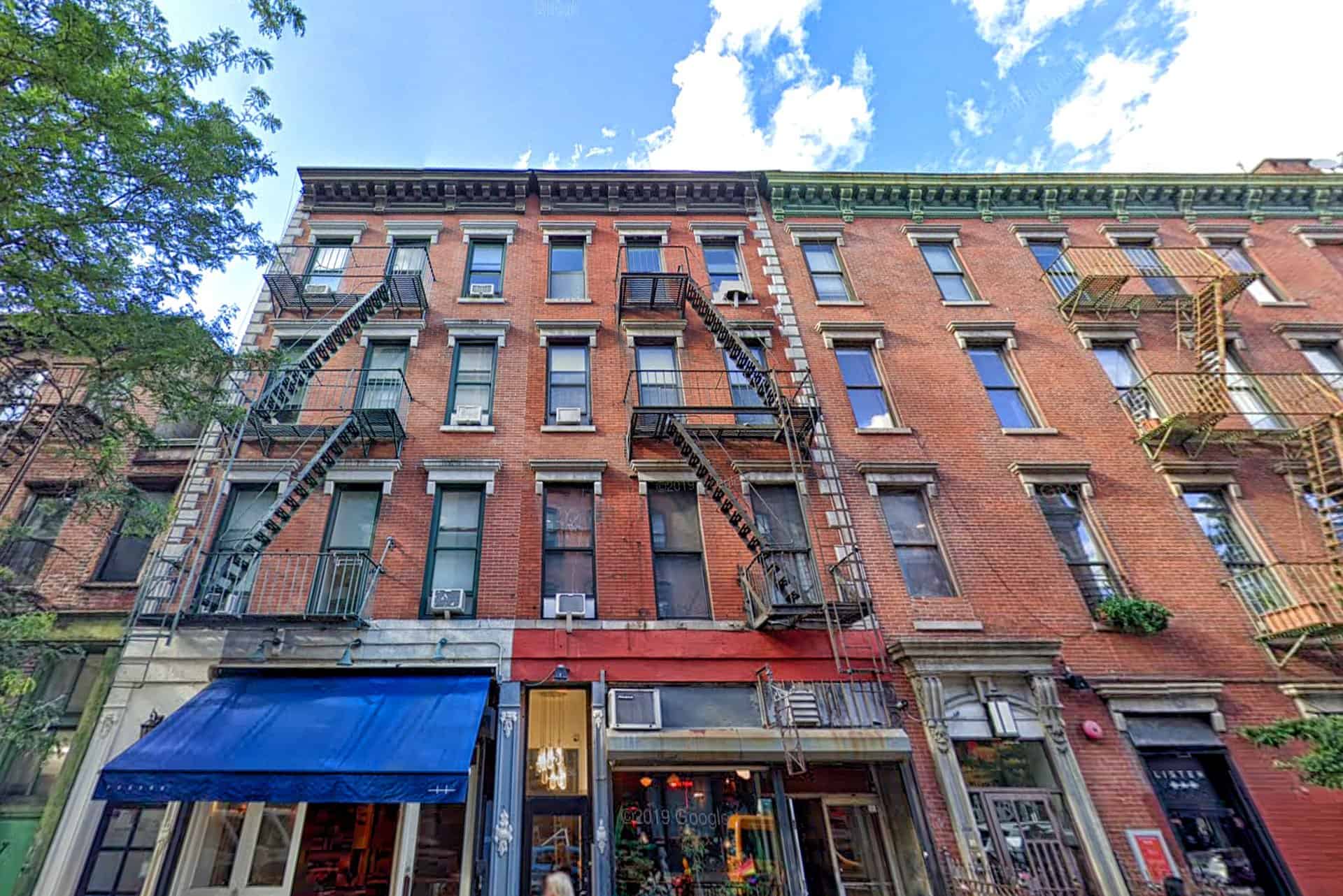Exterior view of 324 Bowery Street & Bleecker Street in NoHo. Brick apartment building with businesses on the ground floor.