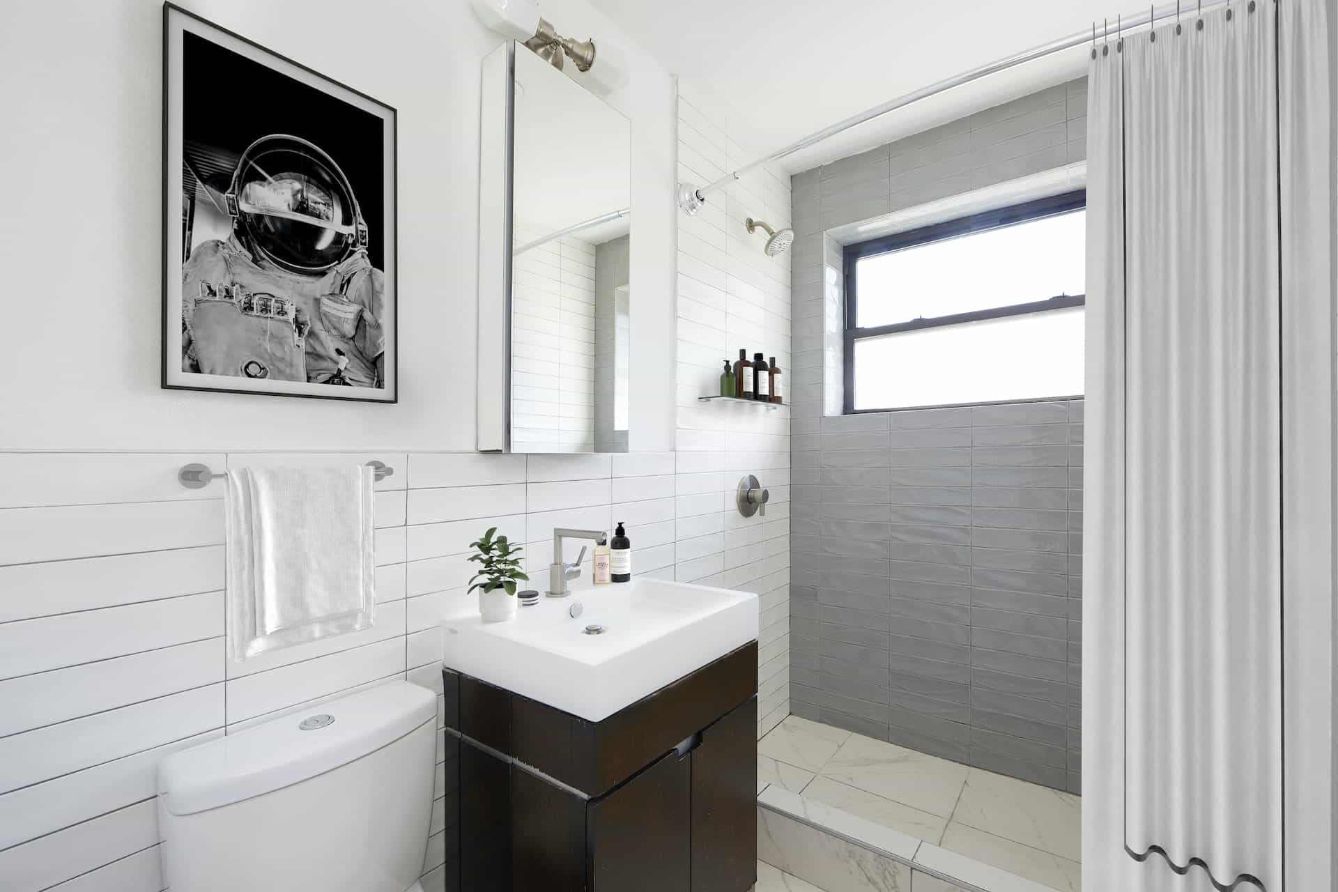 Bathroom at 401 East 50th Street apartments with tile walls, single vanity, a rectangle mirror and walk-in shower.