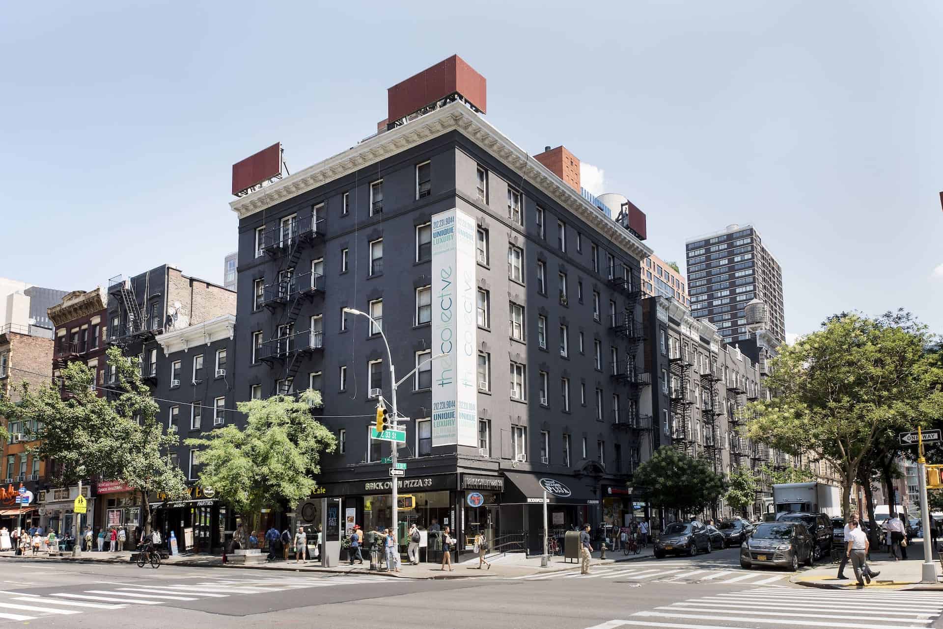 Street view of 207 East 33rd Street apartments in New York. A brick residential building with businesses on the first floor.
