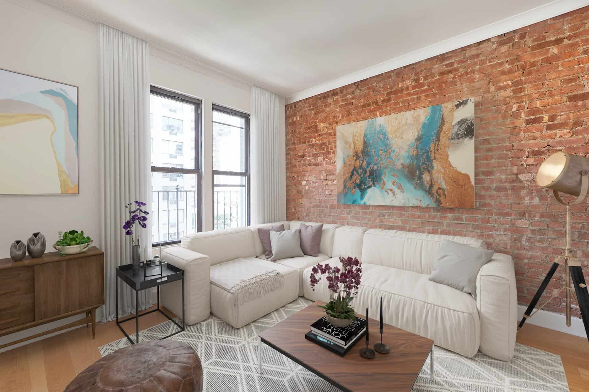 Living room at 207 East 33rd Street apartments. Open room with hardwood floors, a corner couch and a brick accent wall.