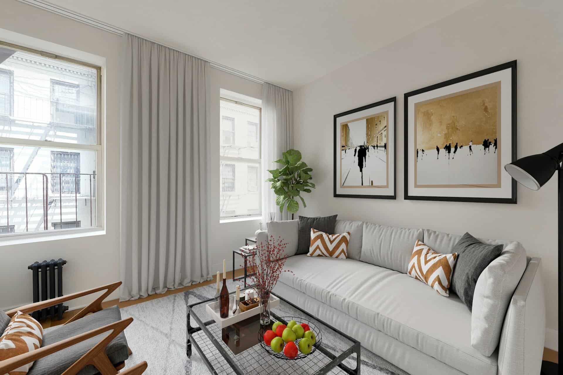 Living room at 207 East 33rd Street apartments with hardwood floors, two tall windows, a couch and glass coffee table.