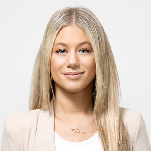 Head shot of Abode Residential licensed real estate agent Tyler Fodiman. Girl with blonde hair, white top and tan jacket.