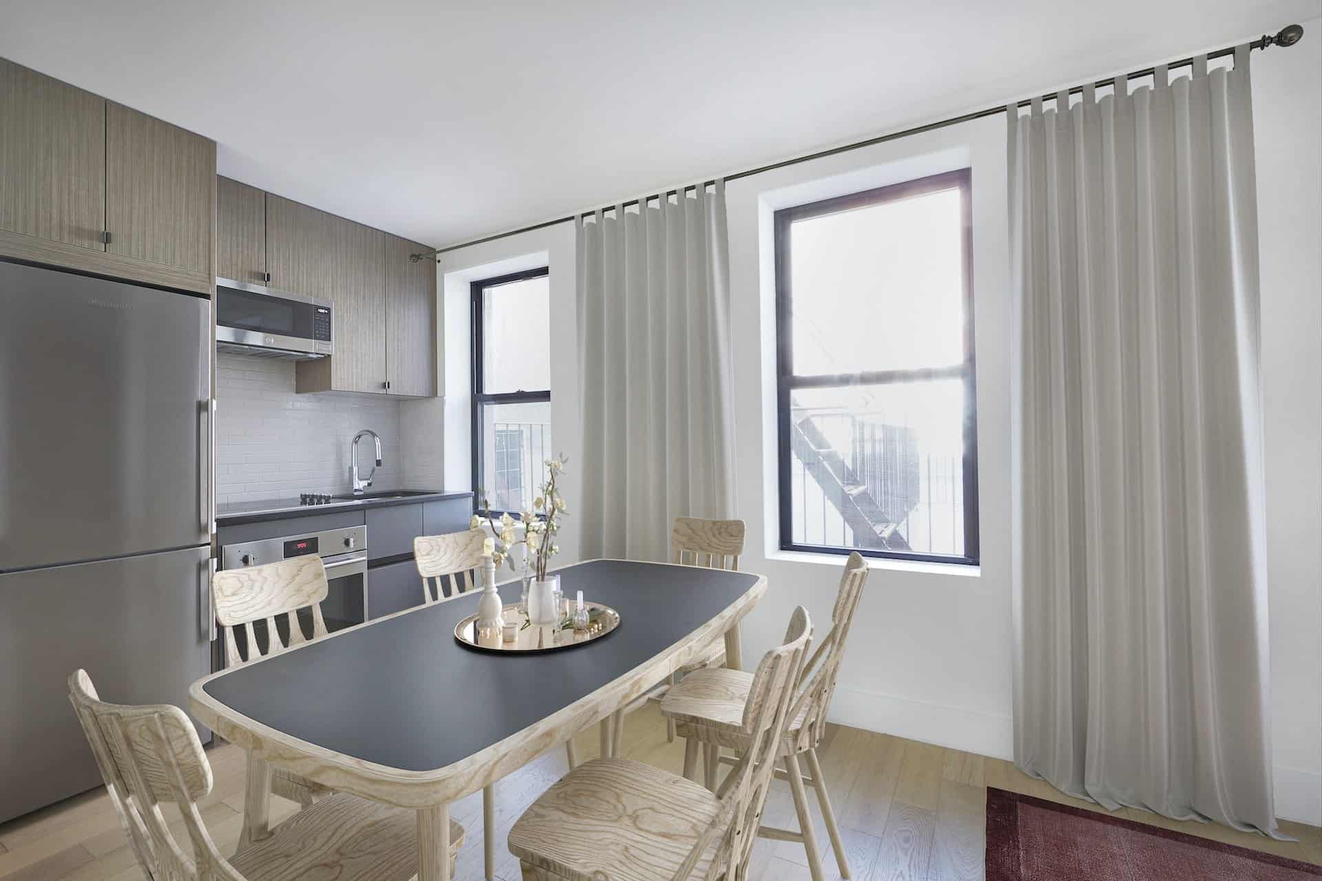 Kitchen at 151-153 Ludlow Street apartments with wood dining table, stainless steel appliances, windows and hardwood floors.