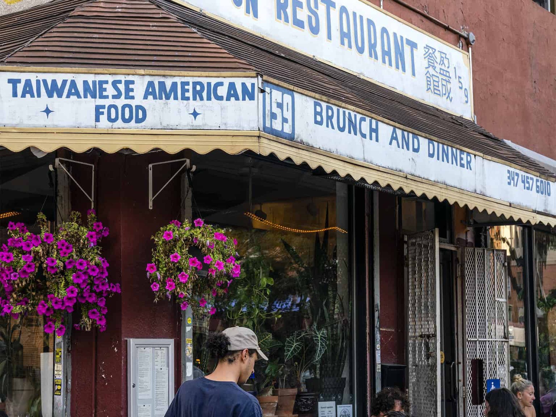 Exterior of Winson Restaurant in New York with people sitting at outdoor tables and a waiter taking someones order.