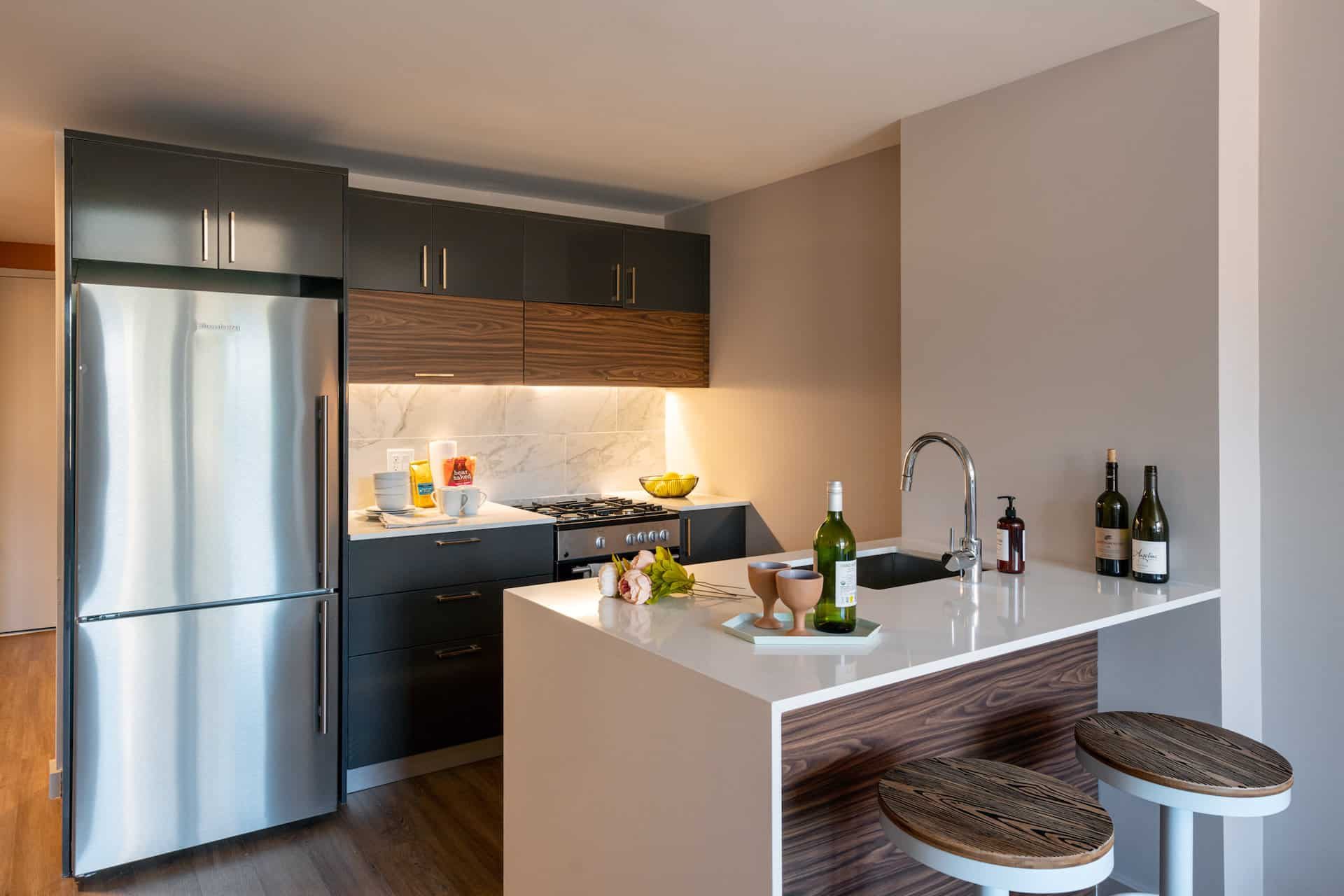 Kitchen at 222 Johnson Avenue apartments with stone countertops, bar seating, stainless steel appliances and hardwood floors.
