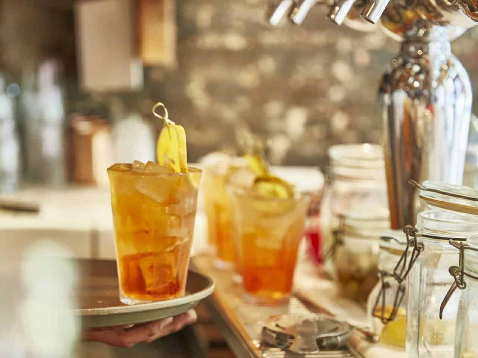 Close up of cocktails on a bar with one on a tray and three on the counter in the background below beer taps.