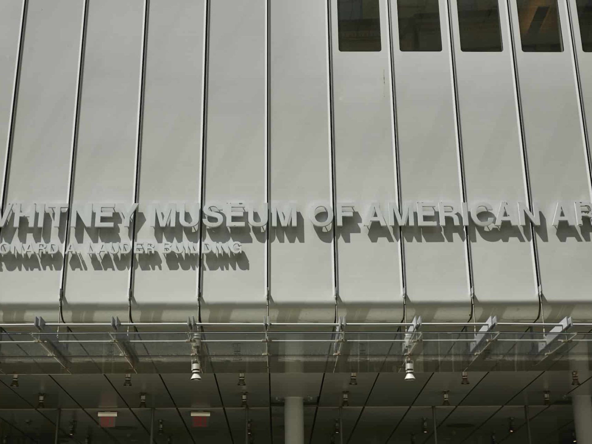 Close up of the Whitney Museum of American Art in New York. Building overhang above the entrance with tall windows.
