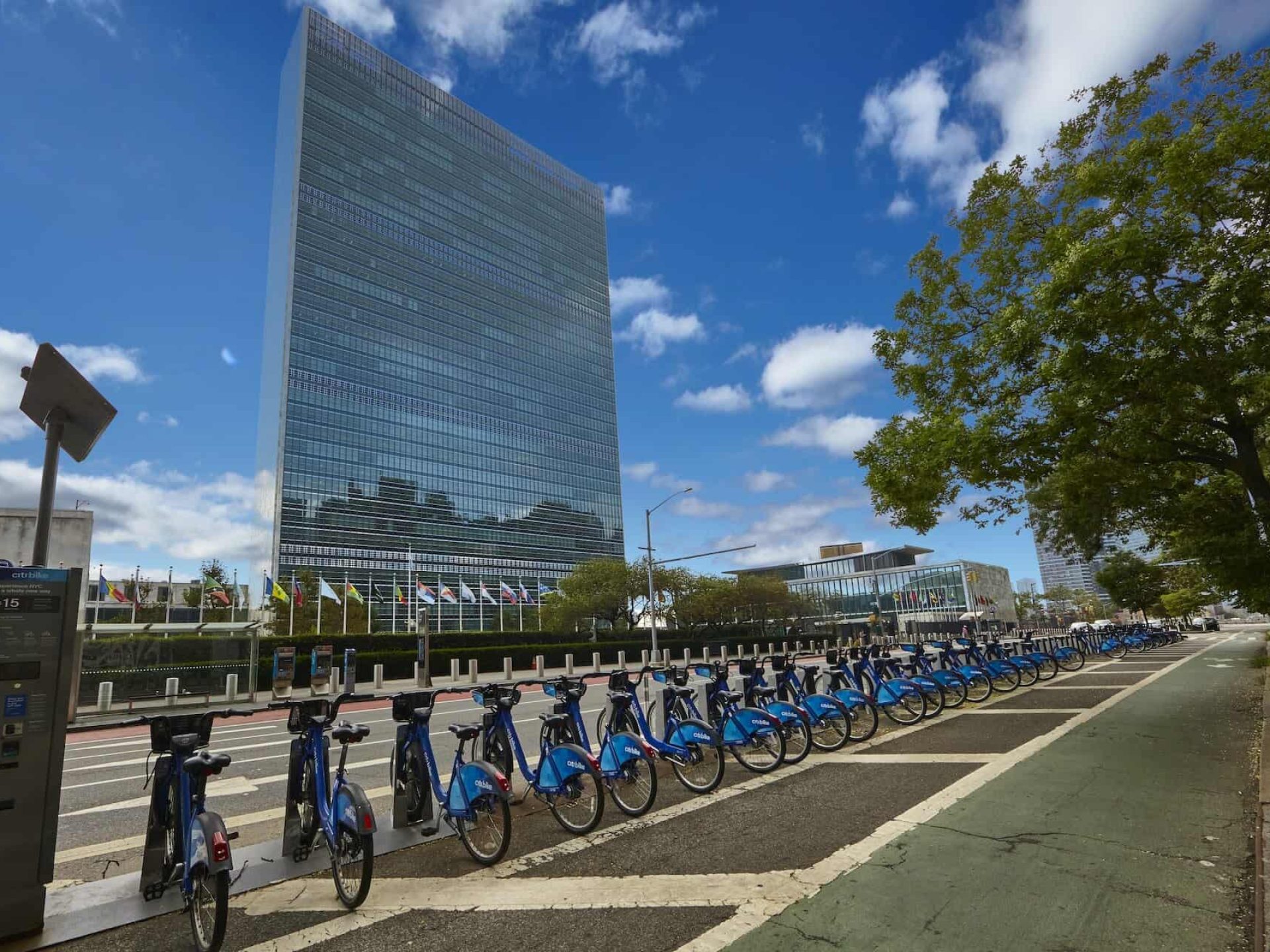 New York City street lined with blue Citi bikes resting in bike racks across the street from the United Nations.