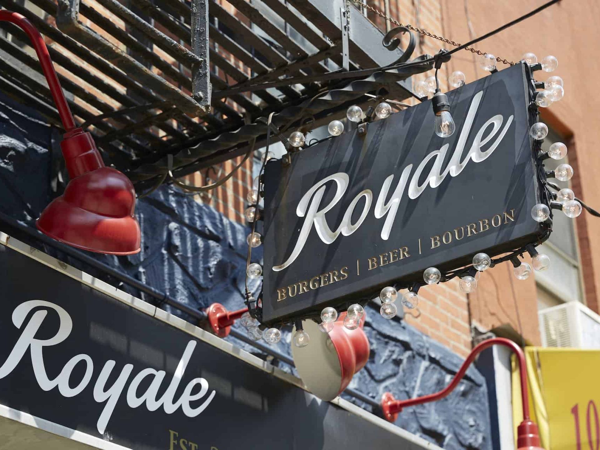 Close up of building sign for Royale burger restaurant in New York's East Village. Black sign with white & yellow lettering.