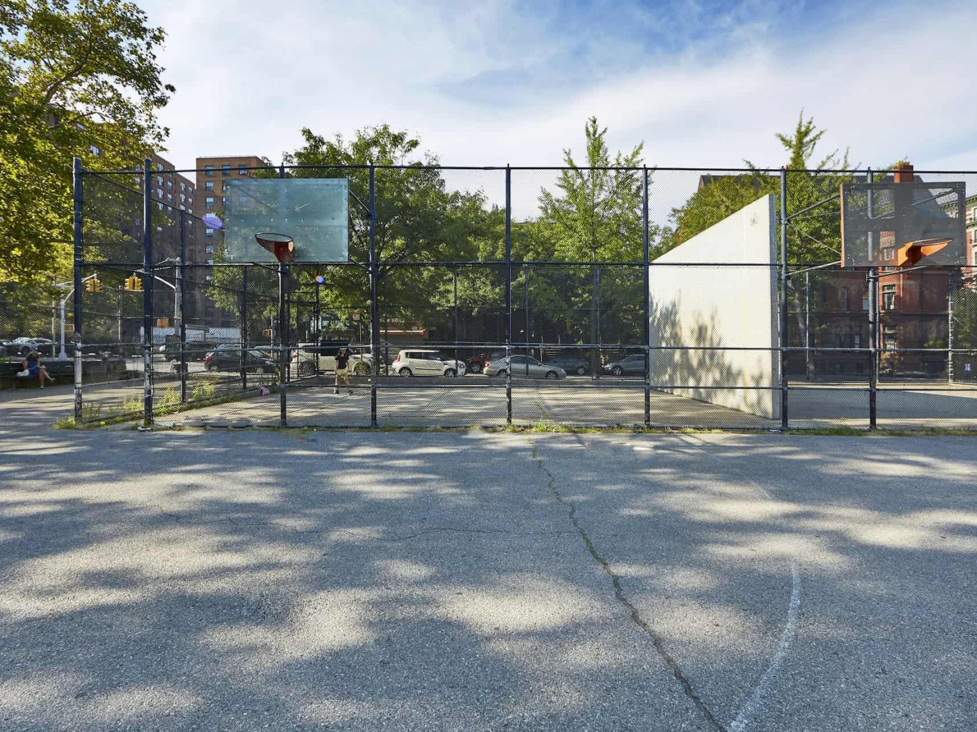 Outdoor basketball court in the Clinton Hill neighborhood. Large paved lot with two basketball hoops and tennis courts.