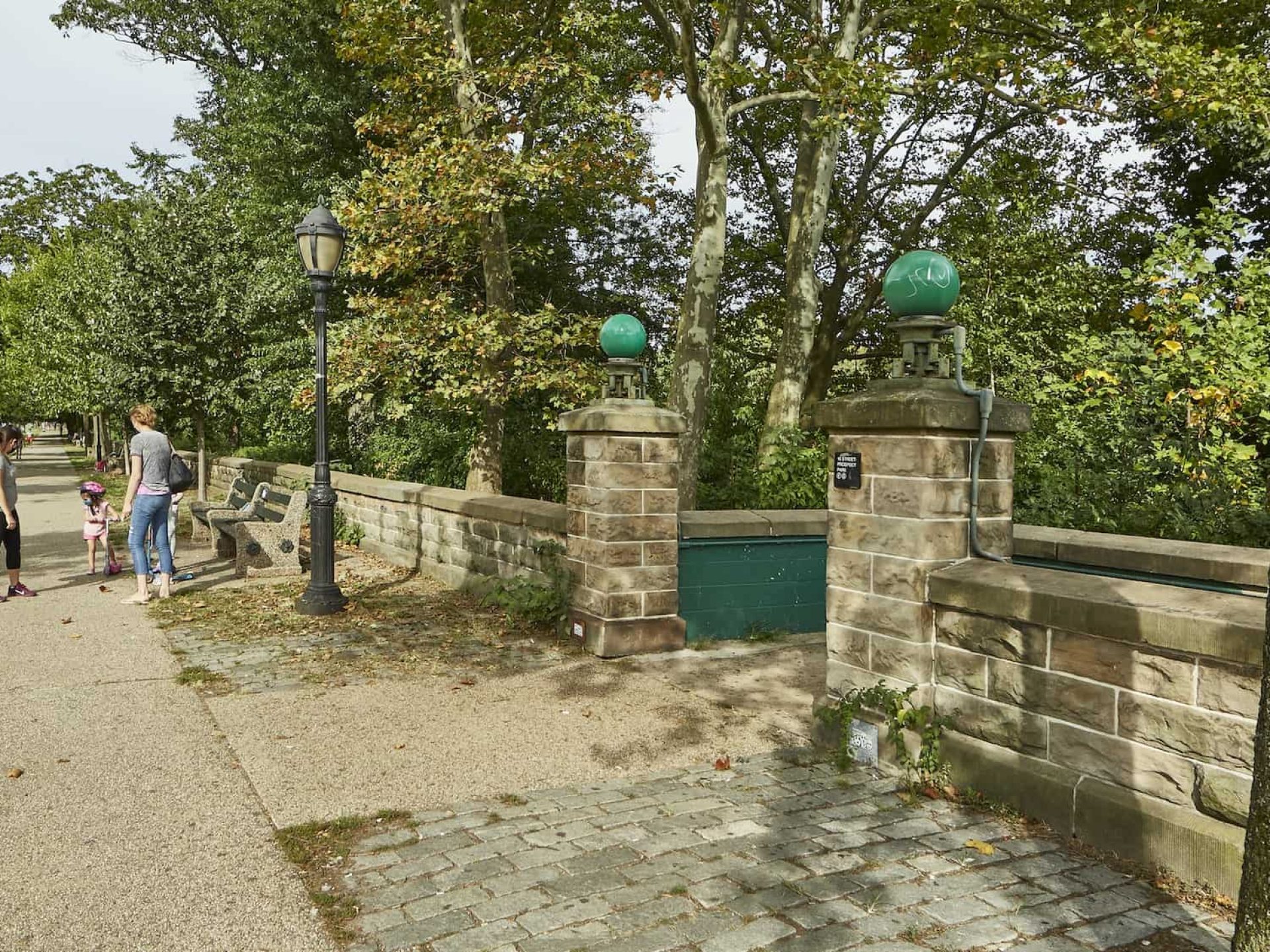 Stone entry and stairs to Prospect Park in Brooklyn, New York. Short pillars at entrance to the park with lights on top.