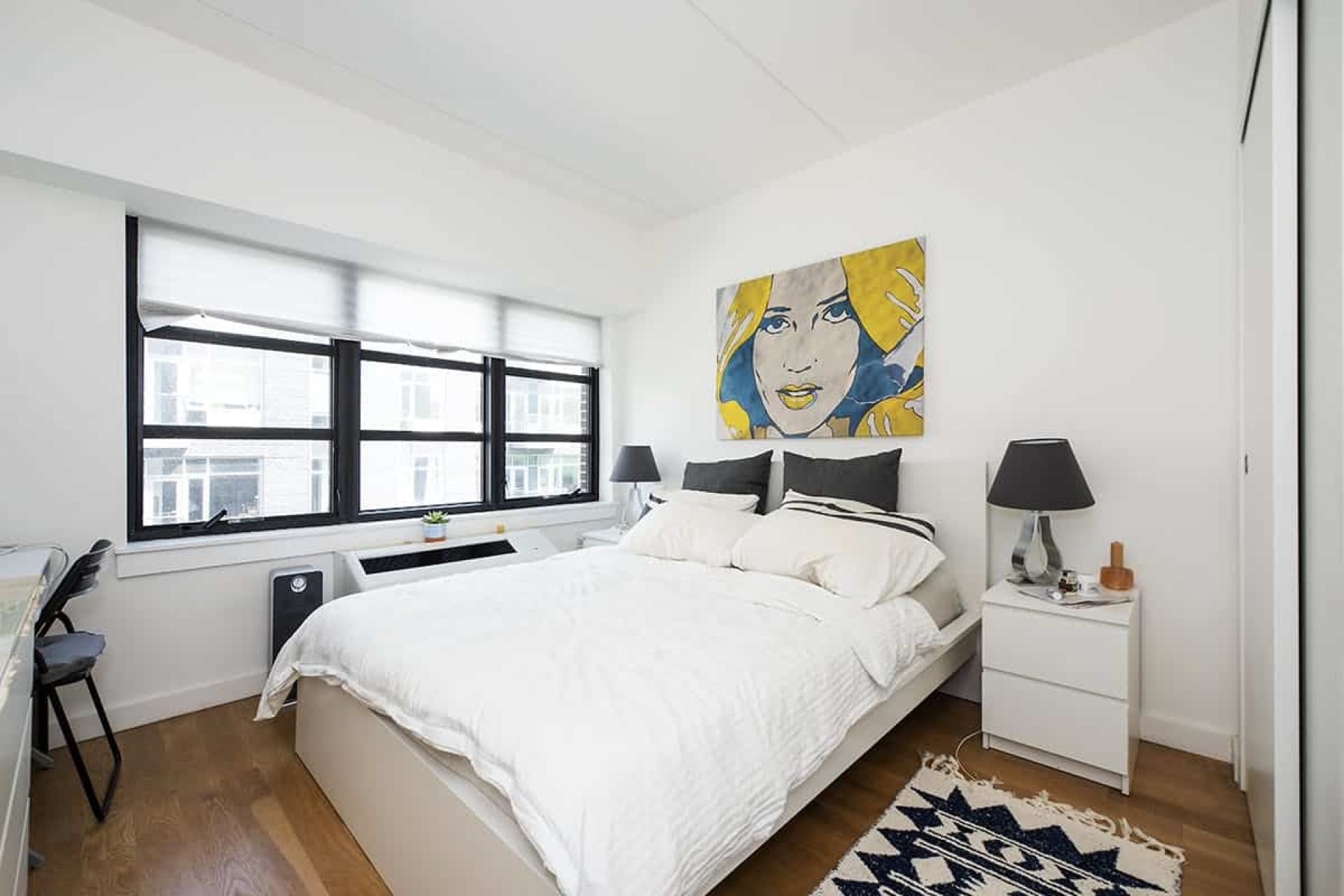 Bedroom at 66 Ainslie Street apartments in Brooklyn with large windows, queen size bed, bed side tables and hardwood floors.