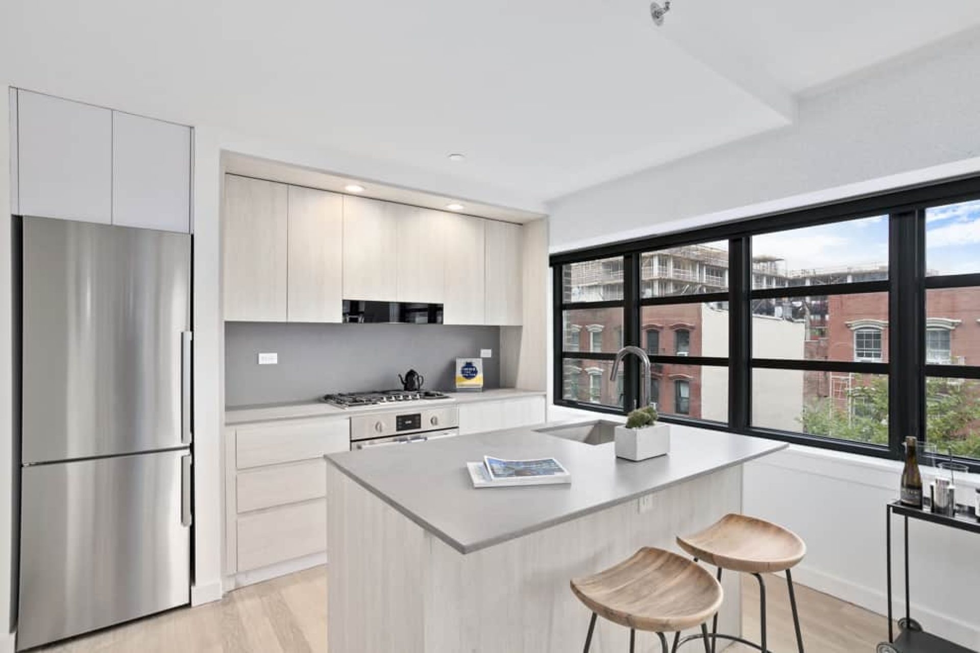 Kitchen at 66 Ainslie Street apartments with a kitchen island, bar seating, stone countertops and stainless steel appliances.