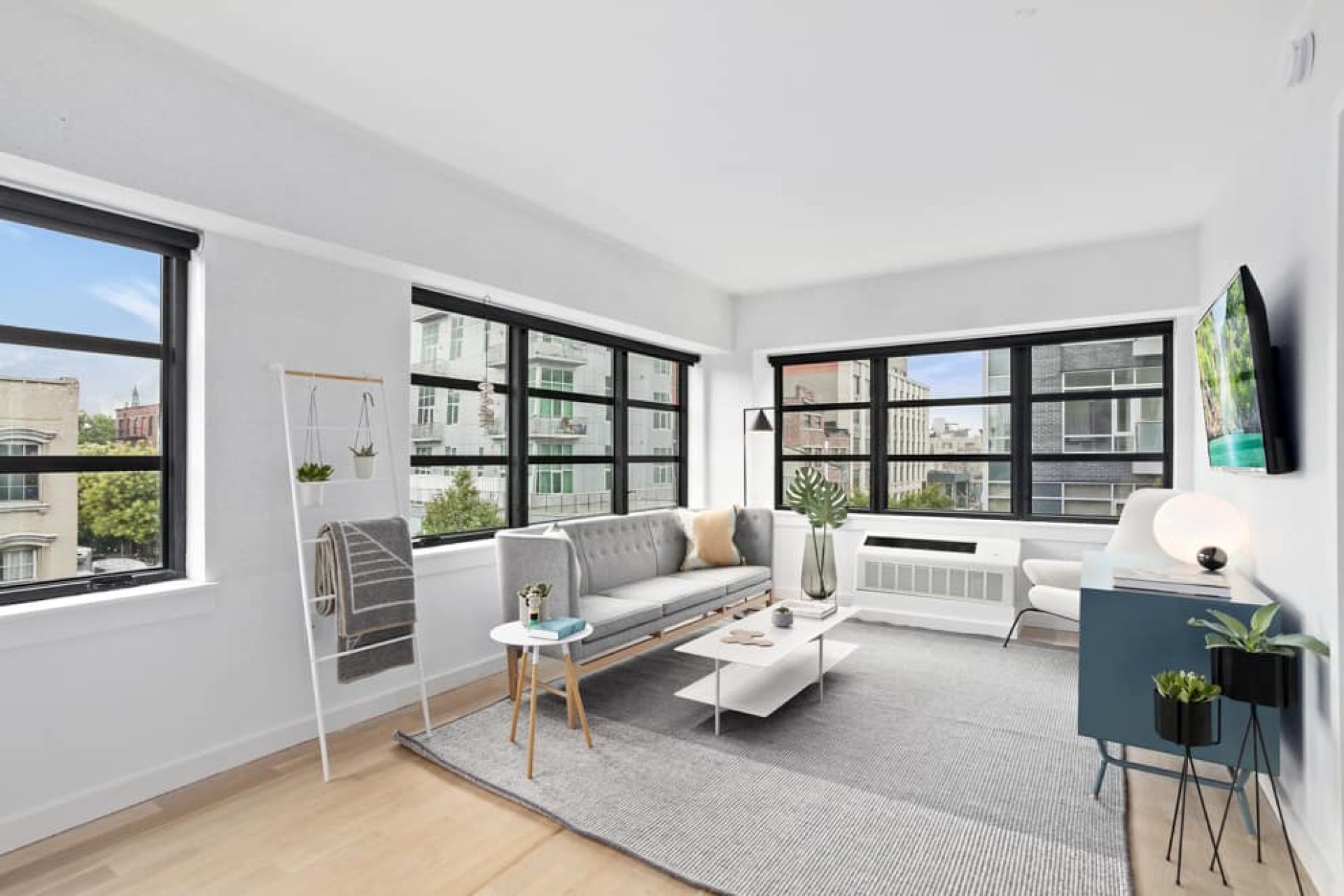 Living room at 66 Ainslie Street apartments with large windows, city views, living room furniture and hardwood floors.
