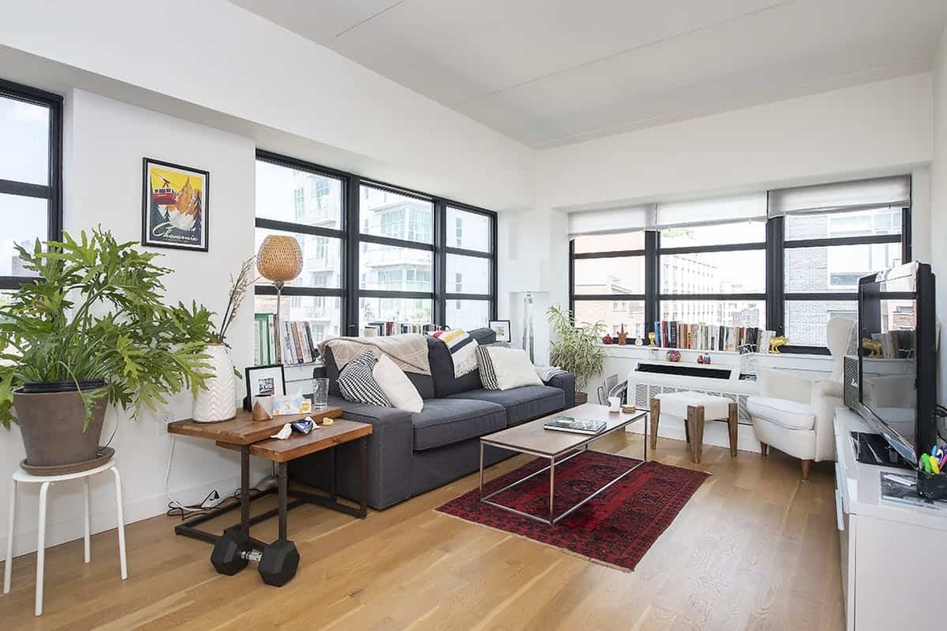 Living room at 66 Ainslie Street apartments in Brooklyn with large windows, a couch with matching tables and hardwood floors.