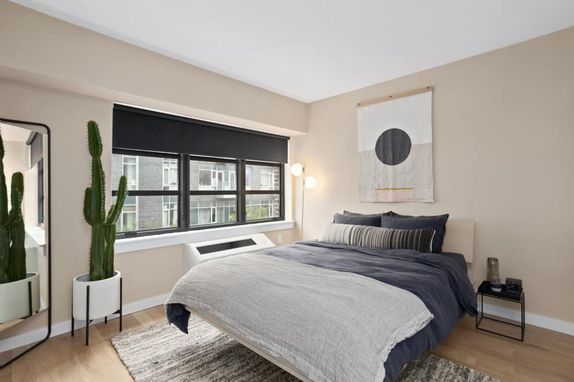 Bedroom at 66 Ainslie Street apartments in Brooklyn with a queen bed, matching bed side tables, mirror and hardwood floors.