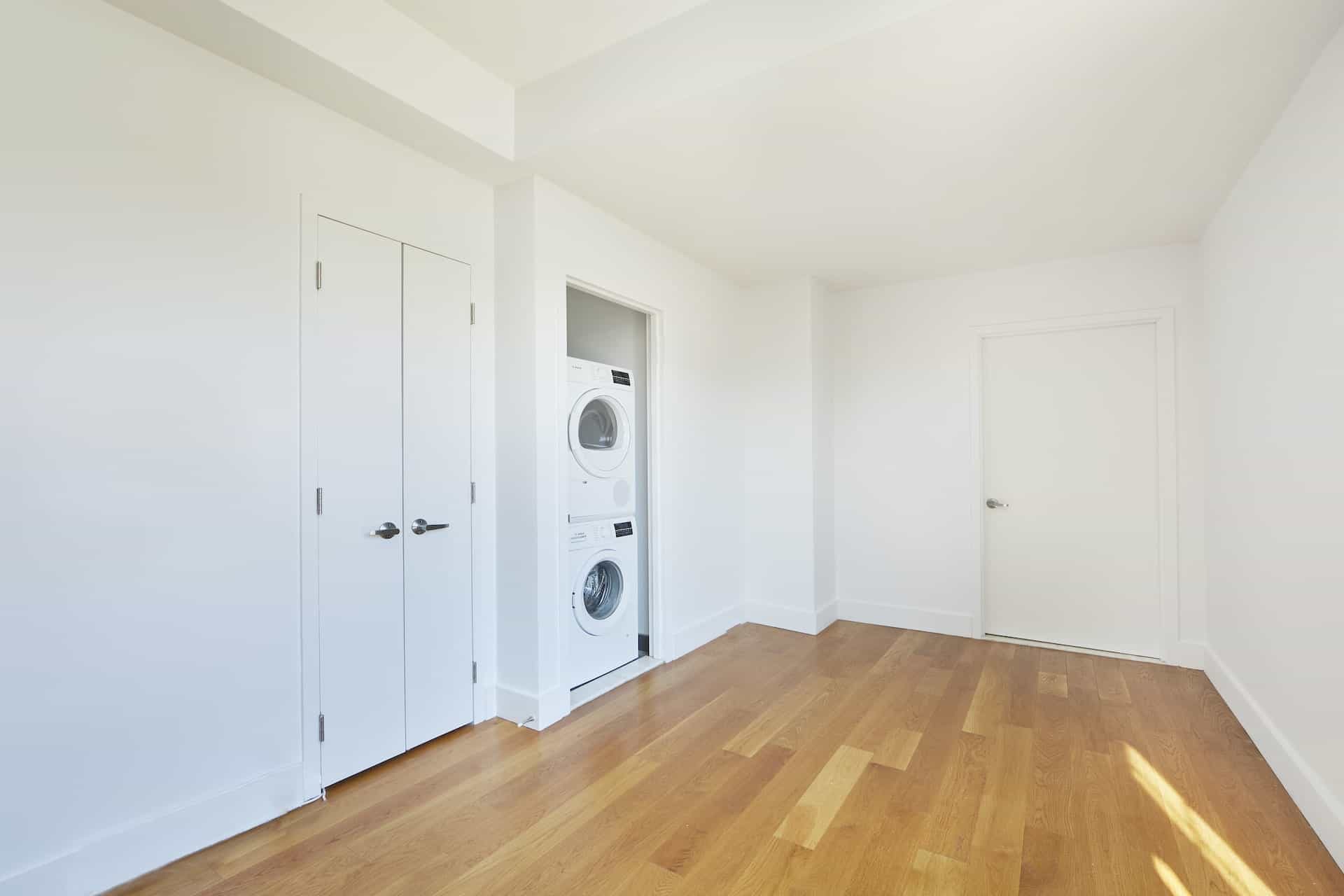 Apartment interior at 83 Bushwick Place in Brooklyn with hardwood floors, a closet, and stacking washer/dryer unit.