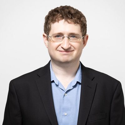 Head shot of Abode Residential licensed real estate agent Ben Fader. Male with brown hair, glasses and wearing a blue shirt.