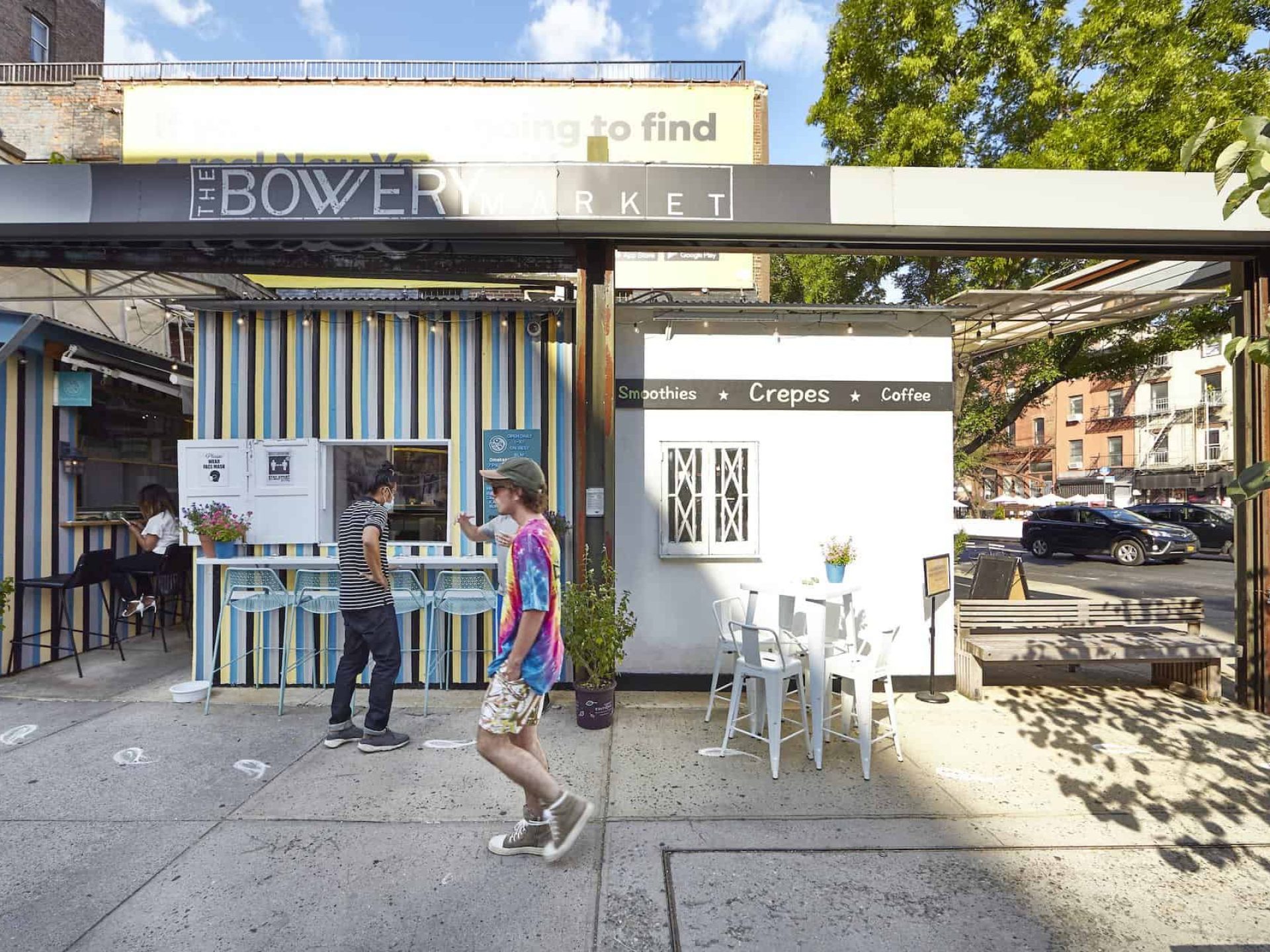 Street view of the Bowery Market in Noho. Street diner offering smoothies, crepes and coffee with people walking by.