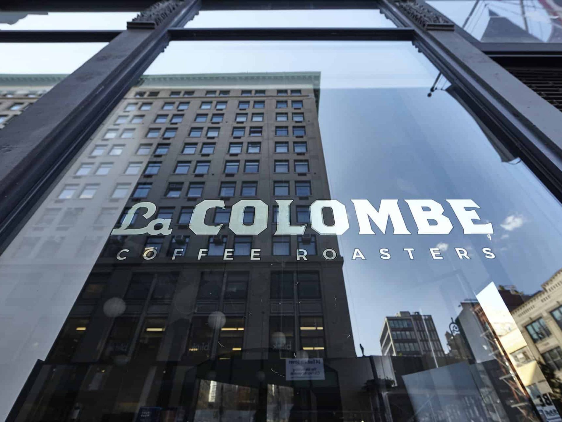 Close up of tall window with decal for "La Colombe Coffee Roasters" in white text with black border.