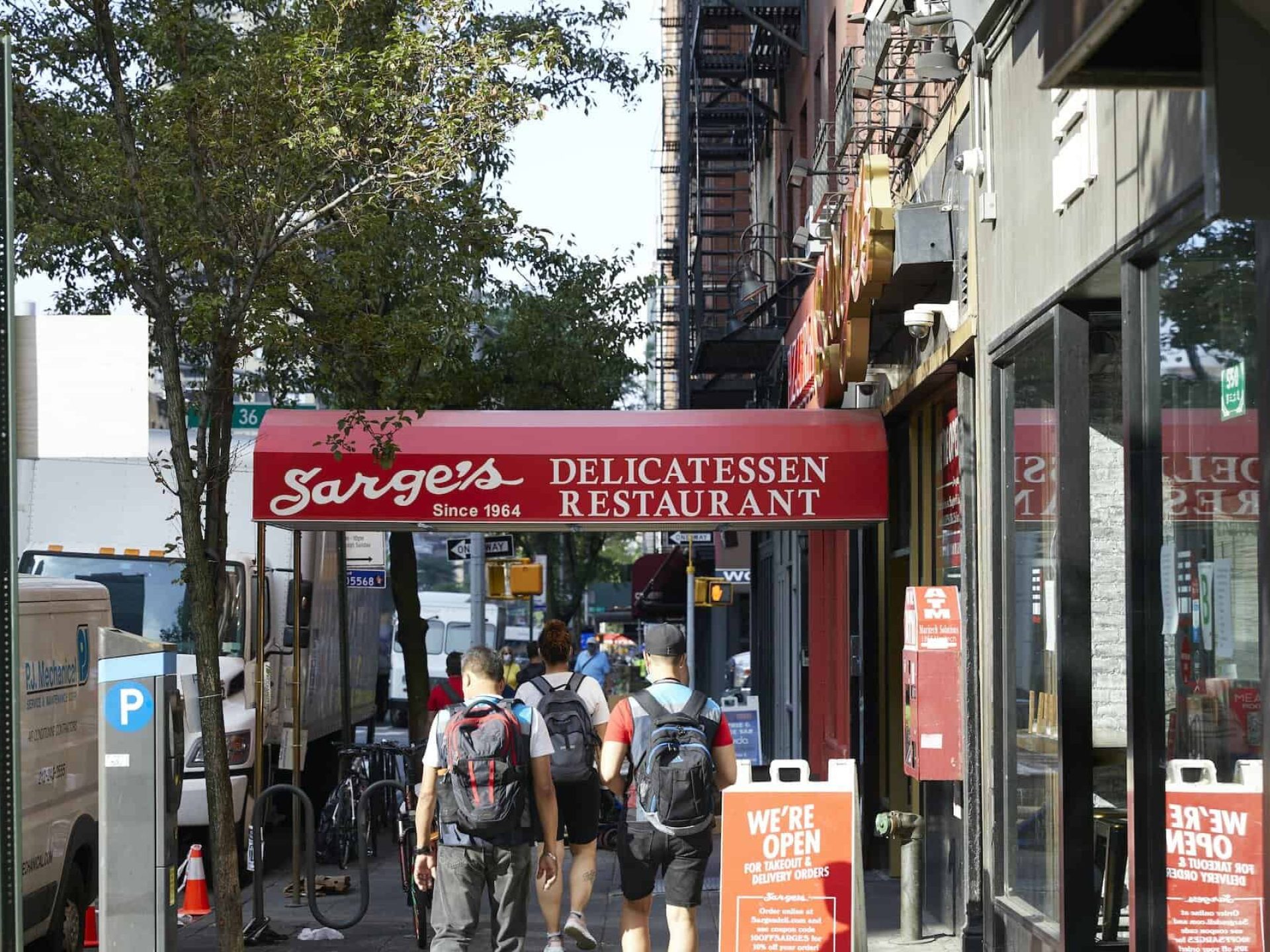 Street view of Sarge's Delicatessen Restaurant with a red awning over the sidewalk with the business name in white letters.