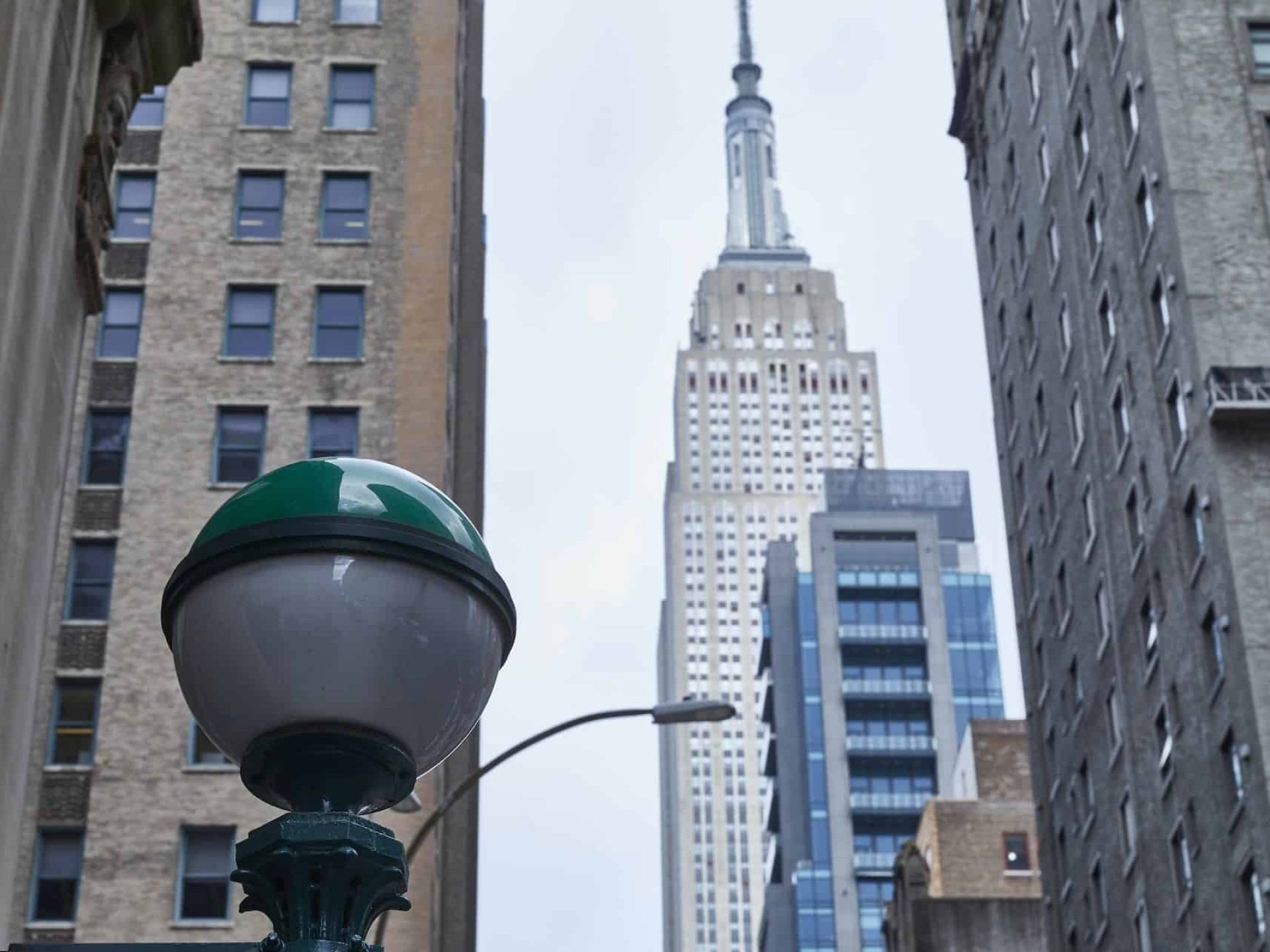 Street view looking up at the Empire State Building in New York City with a street lamp in the foreground.