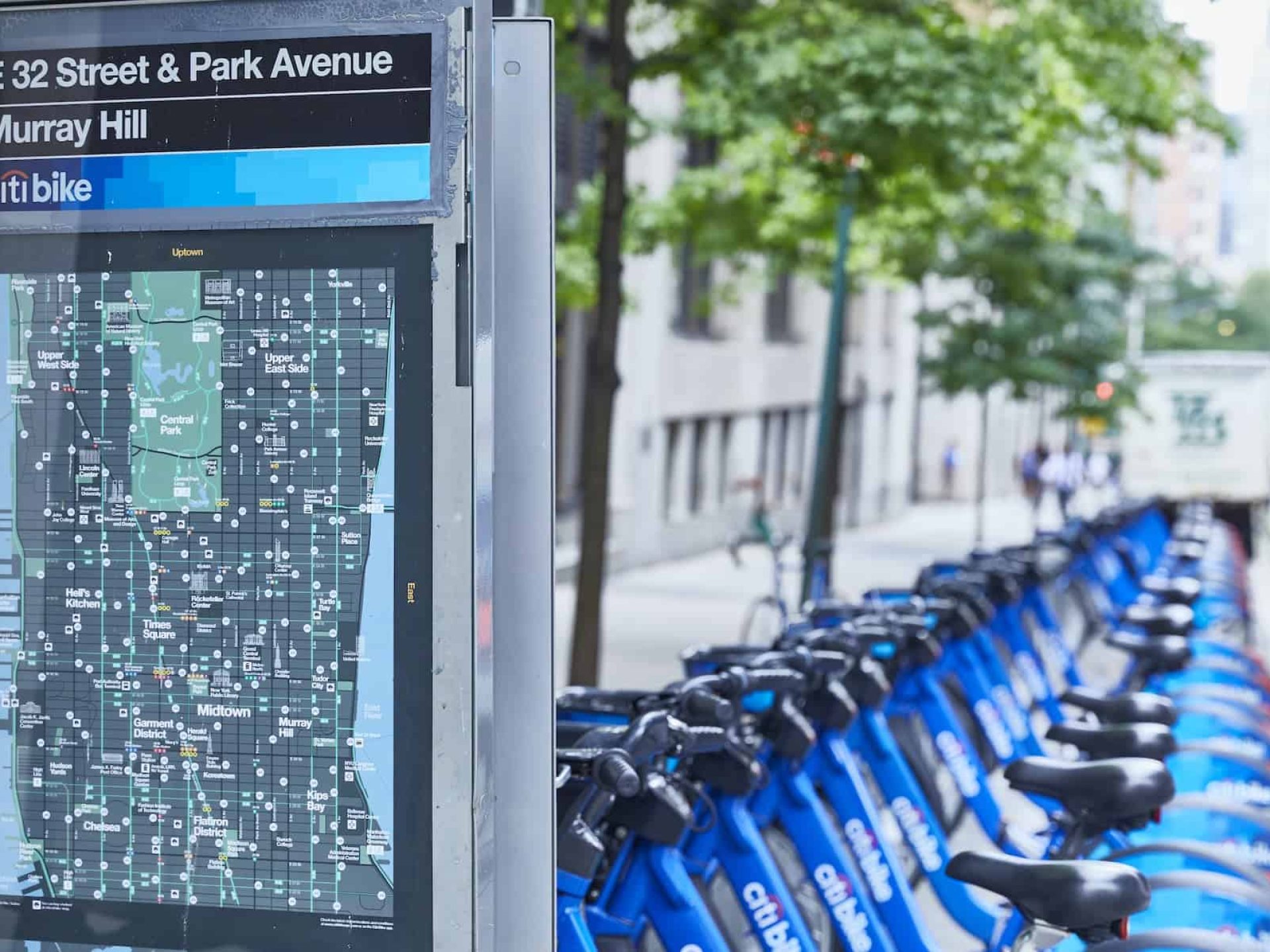 Close up of New York City map with blue Citi bikes in the background. Map shows public transportation information.