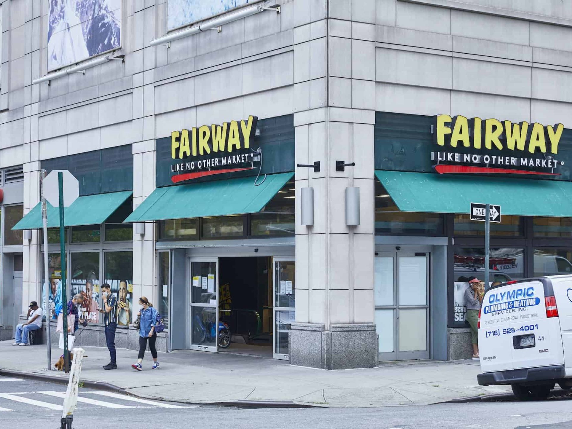 Corner view of Fairway Market in Murray Hill. Open sliding doors covered by green awnings and people on the street.